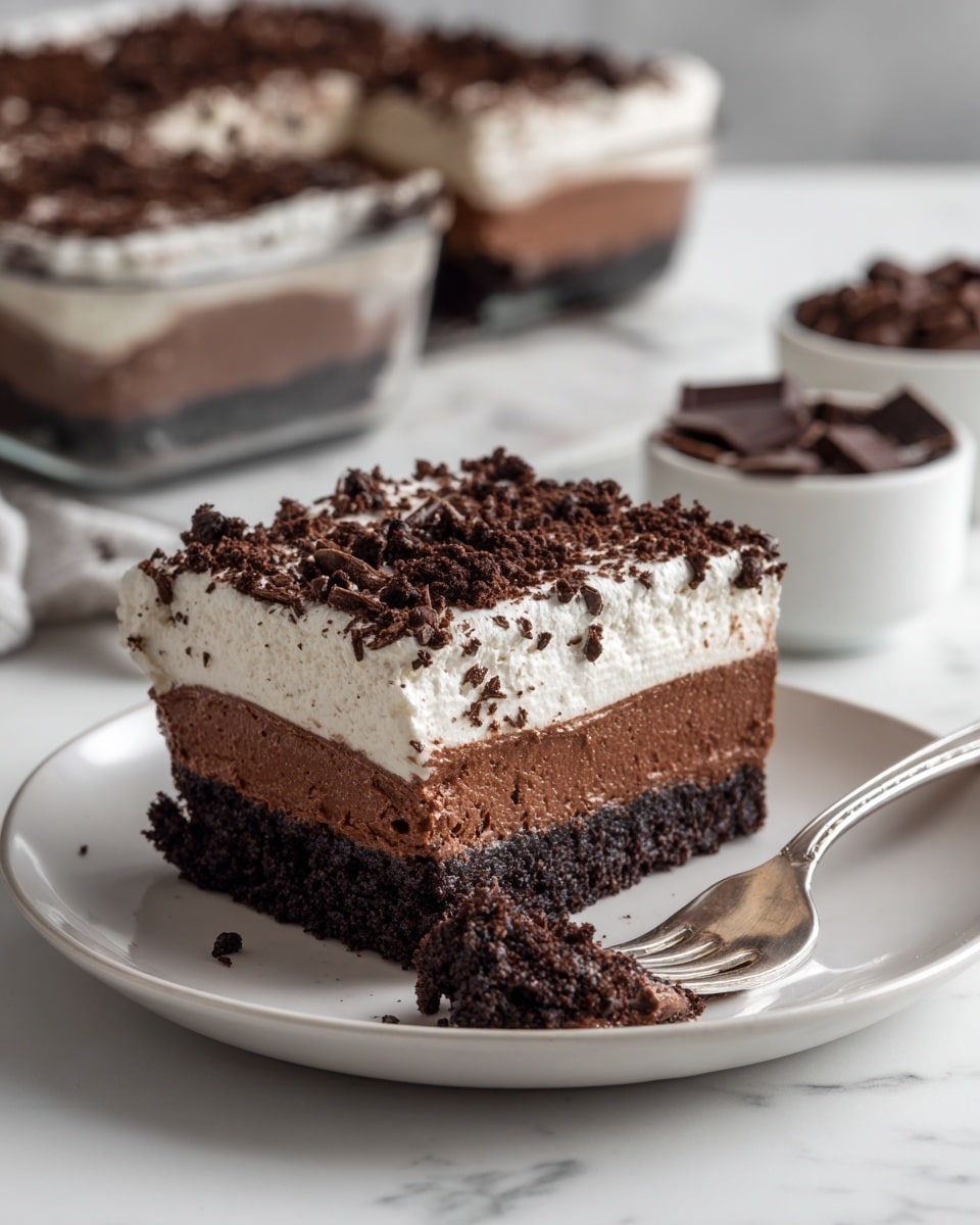 The image shows a three-layered dessert slice on a white plate placed on a white marbled surface. The bottom layer is dark brown with a rich, crumbly texture, resembling a dense chocolate base. The middle layer is a smooth, creamy dark chocolate filling, slightly lighter in color than the base. The top layer is thick, fluffy, and white, looking like whipped cream or a light mousse, sprinkled with small pieces of dark chocolate crumbs for decoration. A silver fork holds a bite-sized portion of the dessert, showing all three layers clearly. In the background, more of the whole dessert is visible in a glass dish, with white bowls containing chocolate pieces nearby. Photo taken with an iphone --ar 4:5 --v 7