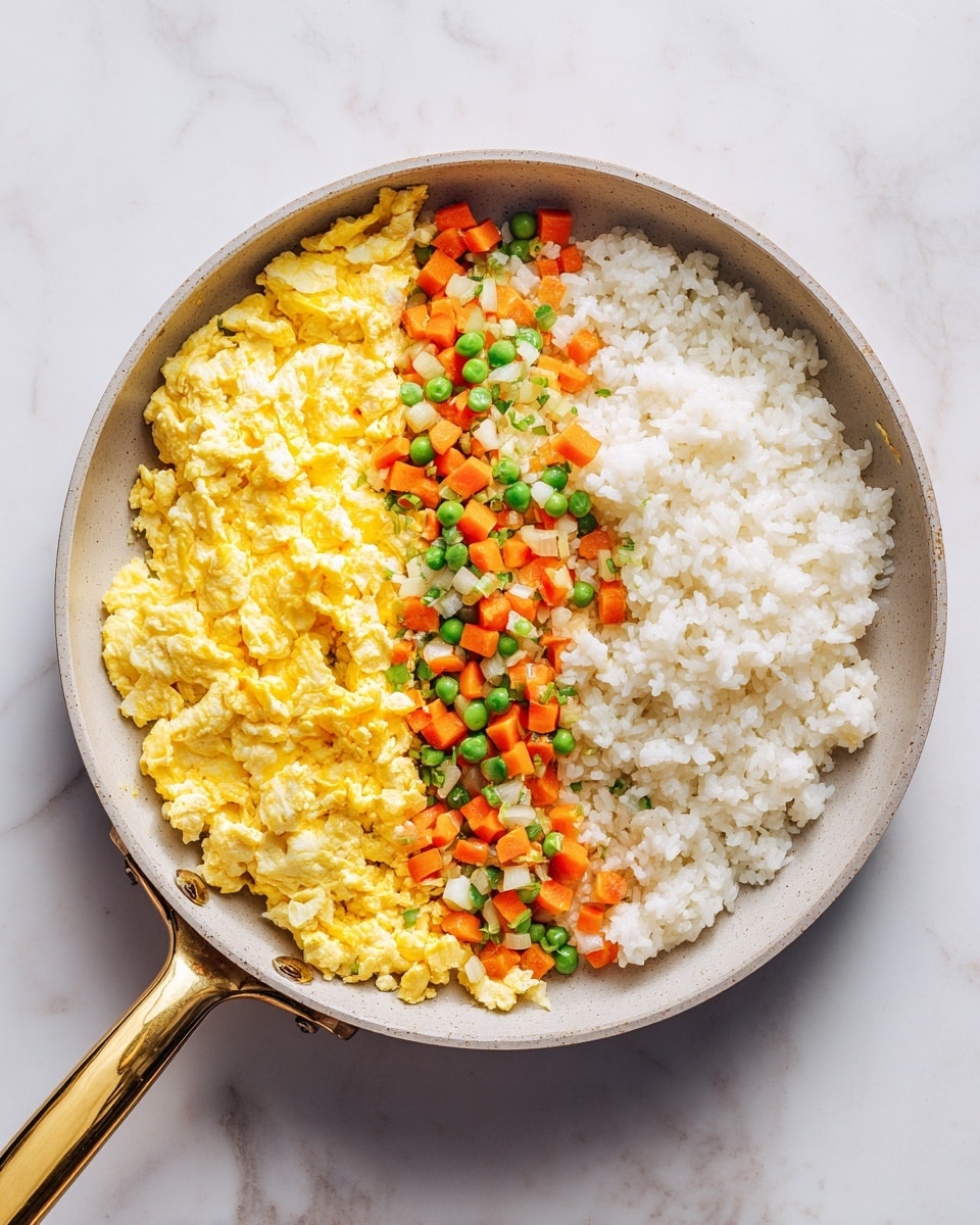 A pan on a white marbled surface has three clear sections of food inside. One section has cooked white rice with a soft, grainy texture, filling about half of the pan. Next to the rice is a thin layer of scrambled eggs, bright yellow with a fluffy and slightly creamy texture, running diagonally across the pan. Alongside the eggs is a mix of small, evenly diced orange carrots, green peas, and bits of white onion, giving a colorful, fresh, and slightly glossy look. The pan has a gold handle and a smooth grey interior. photo taken with an iphone --ar 4:5 --v 7