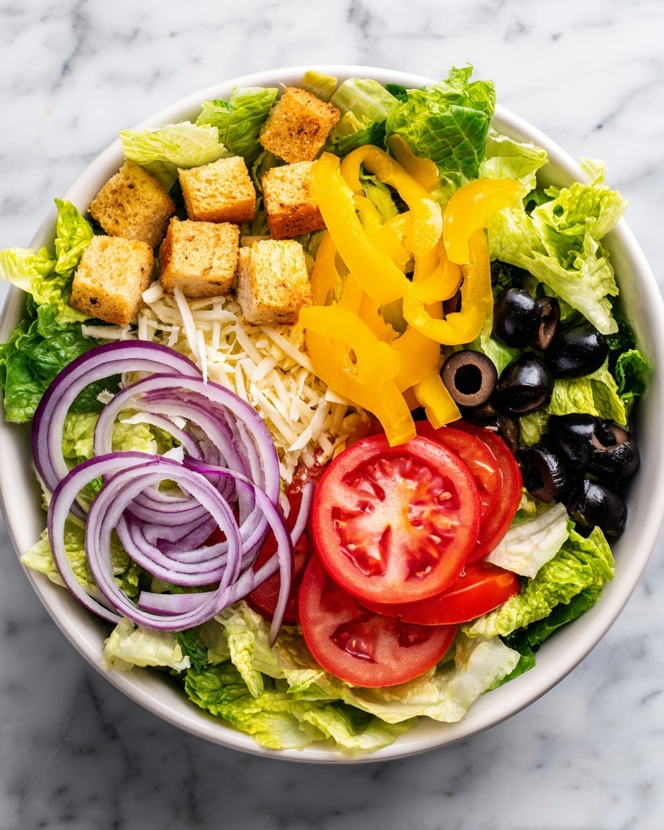 The image shows a fresh salad with several layers of ingredients in a white bowl placed on a white marbled surface. The base layer consists of light green iceberg lettuce leaves with a crisp texture. On top of the lettuce, there are slices of bright red tomatoes and thin rings of purple onion. Black olives add contrast scattered throughout the salad. Yellow pepper slices provide a glossy, smooth layer, with some white shredded cheese sprinkled on top. Small, golden brown croutons add a crunchy texture throughout the salad. The overall look is colorful and fresh with a mix of crisp, juicy, and crunchy elements photo taken with an iphone --ar 4:5 --v 7