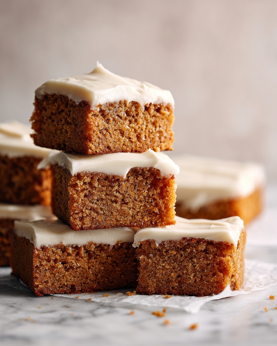 The image shows a stack of three square pieces of moist carrot cake with a light cream cheese frosting layer on top of each piece. The carrot cake layers are orange-brown and soft with a slightly crumbly texture. The frosting is smooth and creamy, light beige in color, and evenly spread, slightly dripping over the edges. To the left, a larger tray of similar frosted pieces is visible, all sitting on a parchment paper-covered surface with a white marbled texture. The background is softly blurred with warm tones. photo taken with an iphone --ar 4:5 --v 7