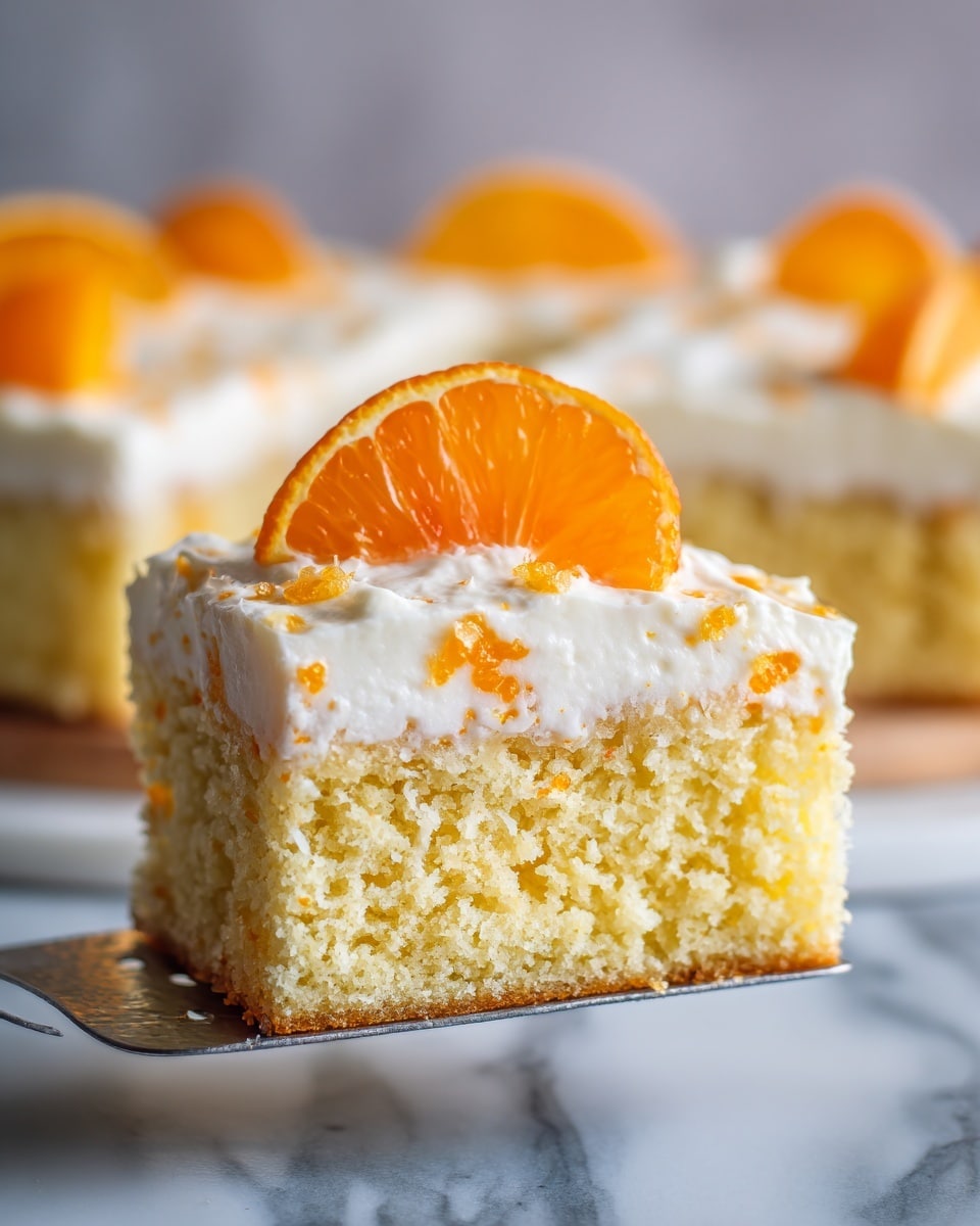 The image shows a square piece of yellow cake with a soft, spongy texture as the bottom layer. On top of this cake is a thick layer of white creamy frosting with small bits of orange mixed inside, giving it a slightly textured look. A bright orange mandarin slice is placed in the center on top of the frosting. The cake is held by a metal spatula above a white marbled surface, and the rest of the cake with the same layers and frosting is visible in the background. Photo taken with an iphone --ar 4:5 --v 7