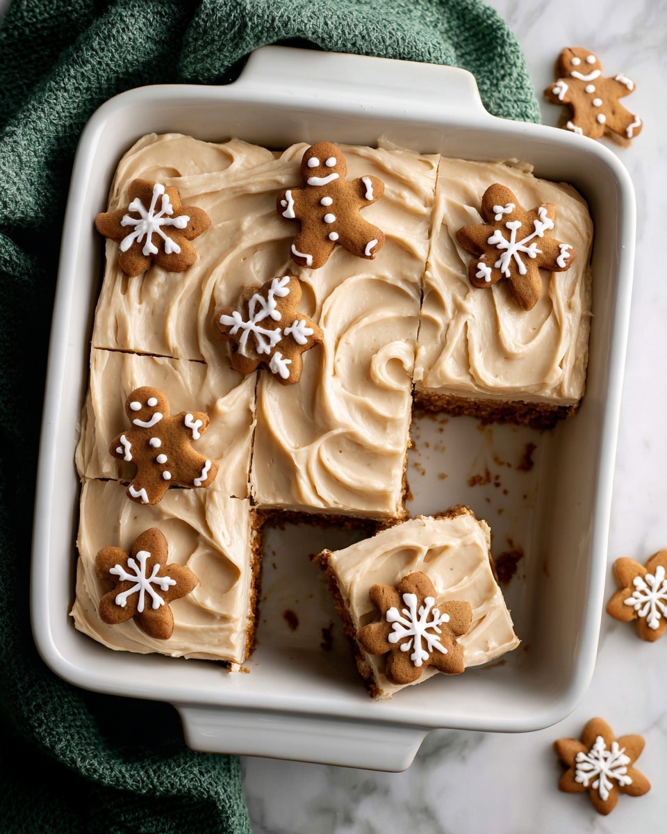 A white rectangular baking dish filled with a dessert cut into six square pieces, each layered with smooth, creamy, light tan frosting that has soft swirls on top. On top of the dessert, small gingerbread cookies shaped like men and snowflakes are placed in a scattered pattern, decorated with simple white icing details. The dish is set on a white marbled surface with a green cloth in the background. photo taken with an iphone --ar 4:5 --v 7